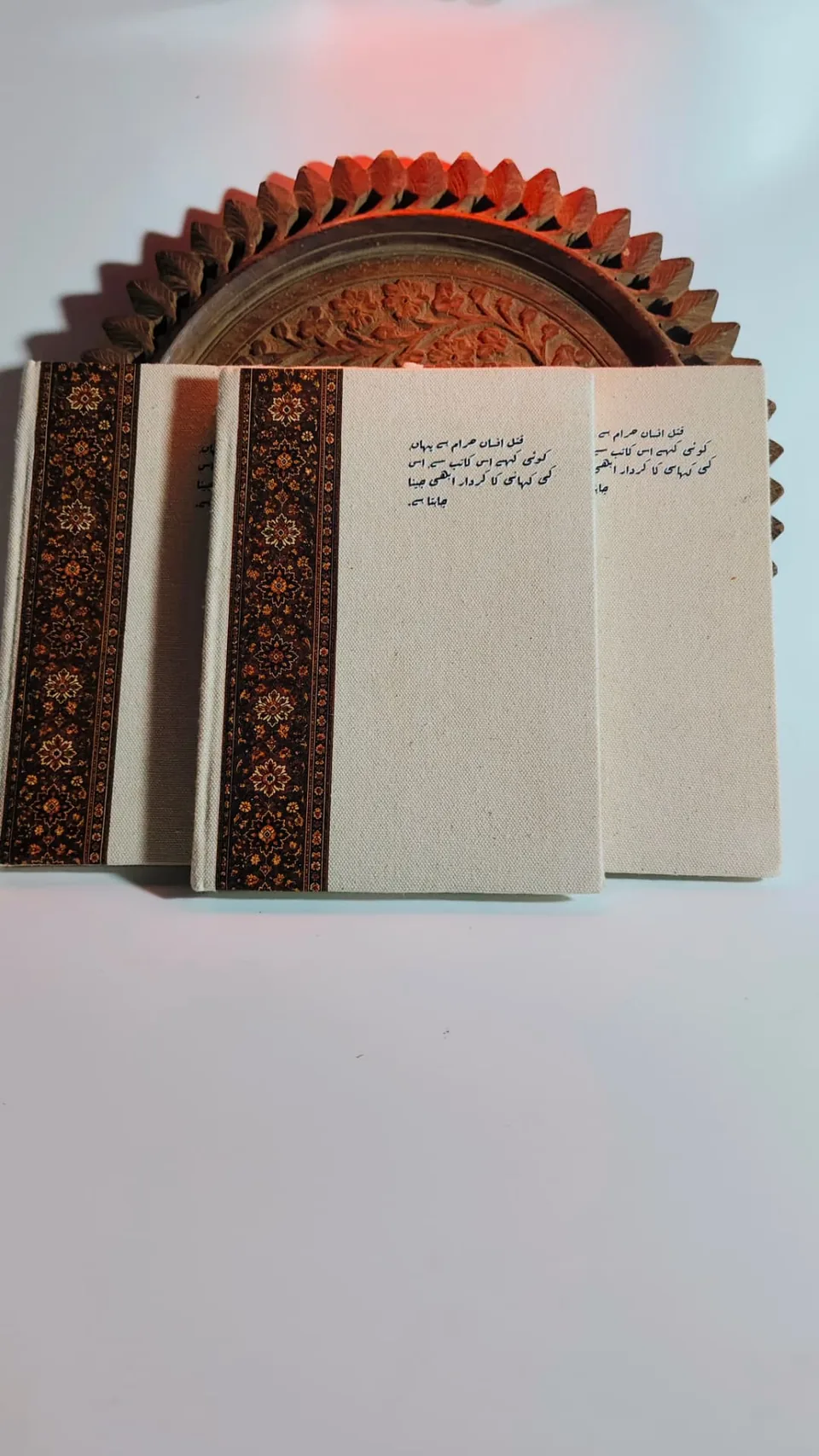 Three Kaatib diaries fanned out beside a carved wooden tray